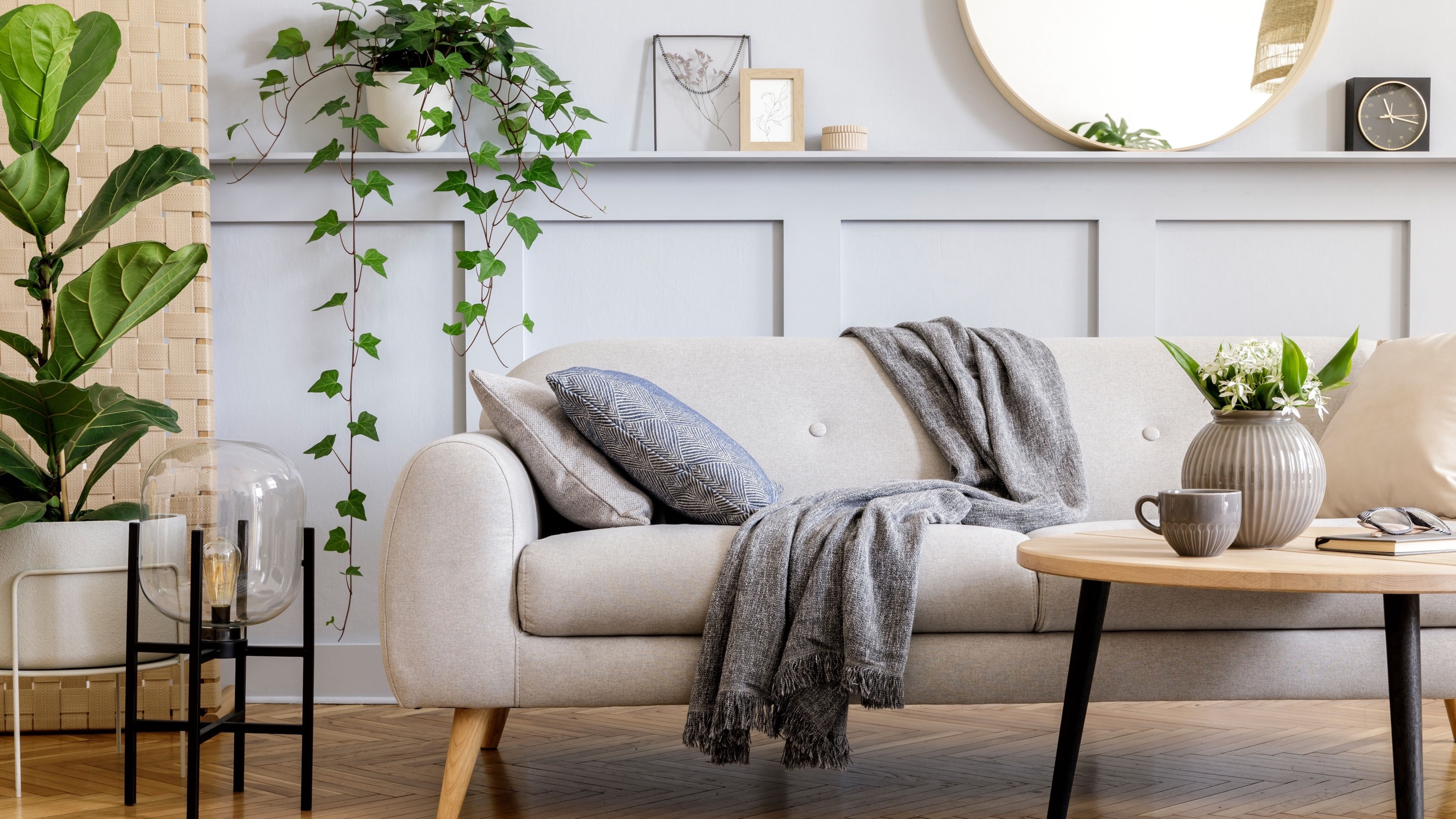 Scandinavian-concept-of-living-room-interior-with-design-sofa,-coffee-table,-plant-in-pot,-flowers,-carpet,-plaid,-pillow,-shelf,-decoration-and-personal-accessories-in-modern-home-staging